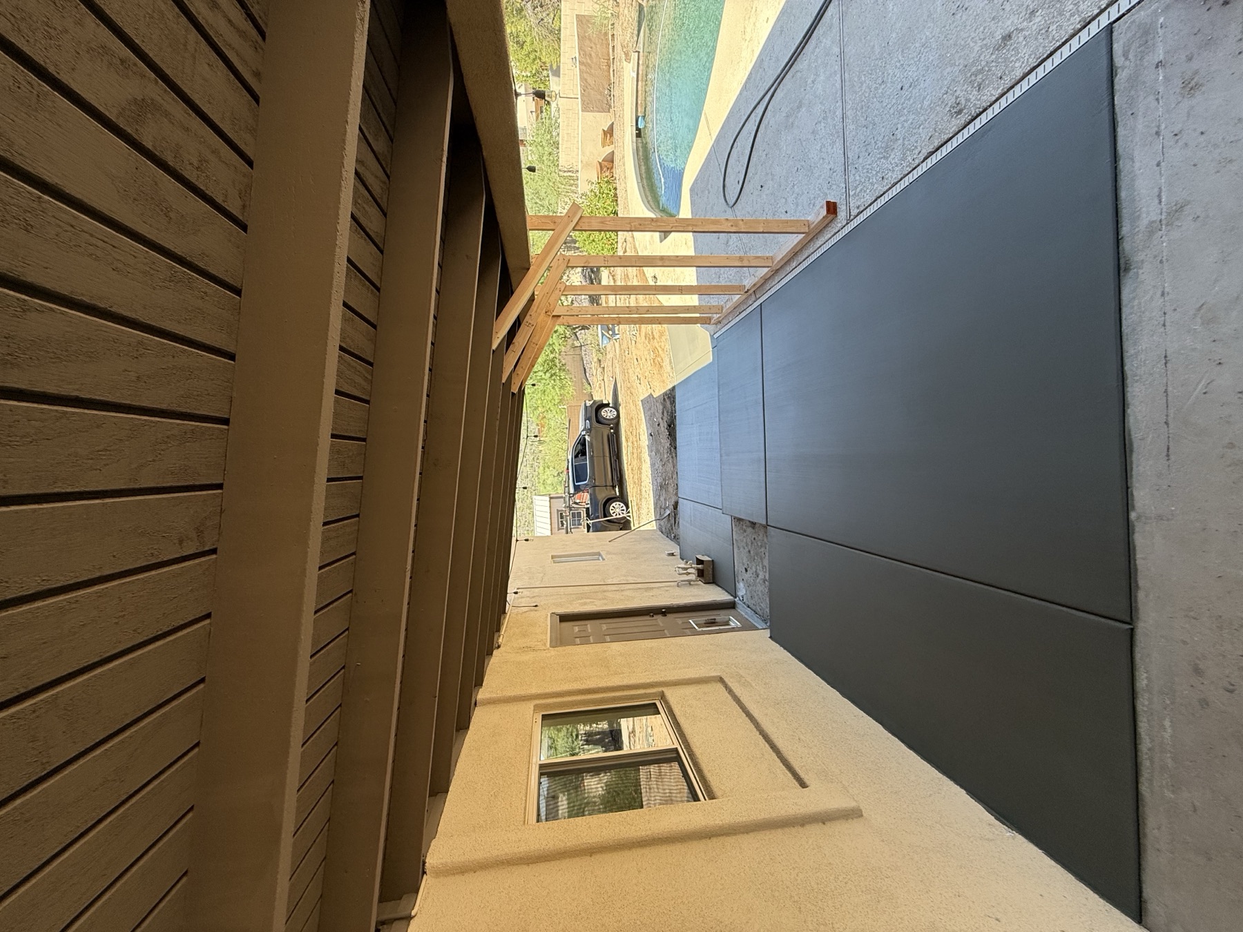 Covered walkway with stained concrete beside pool