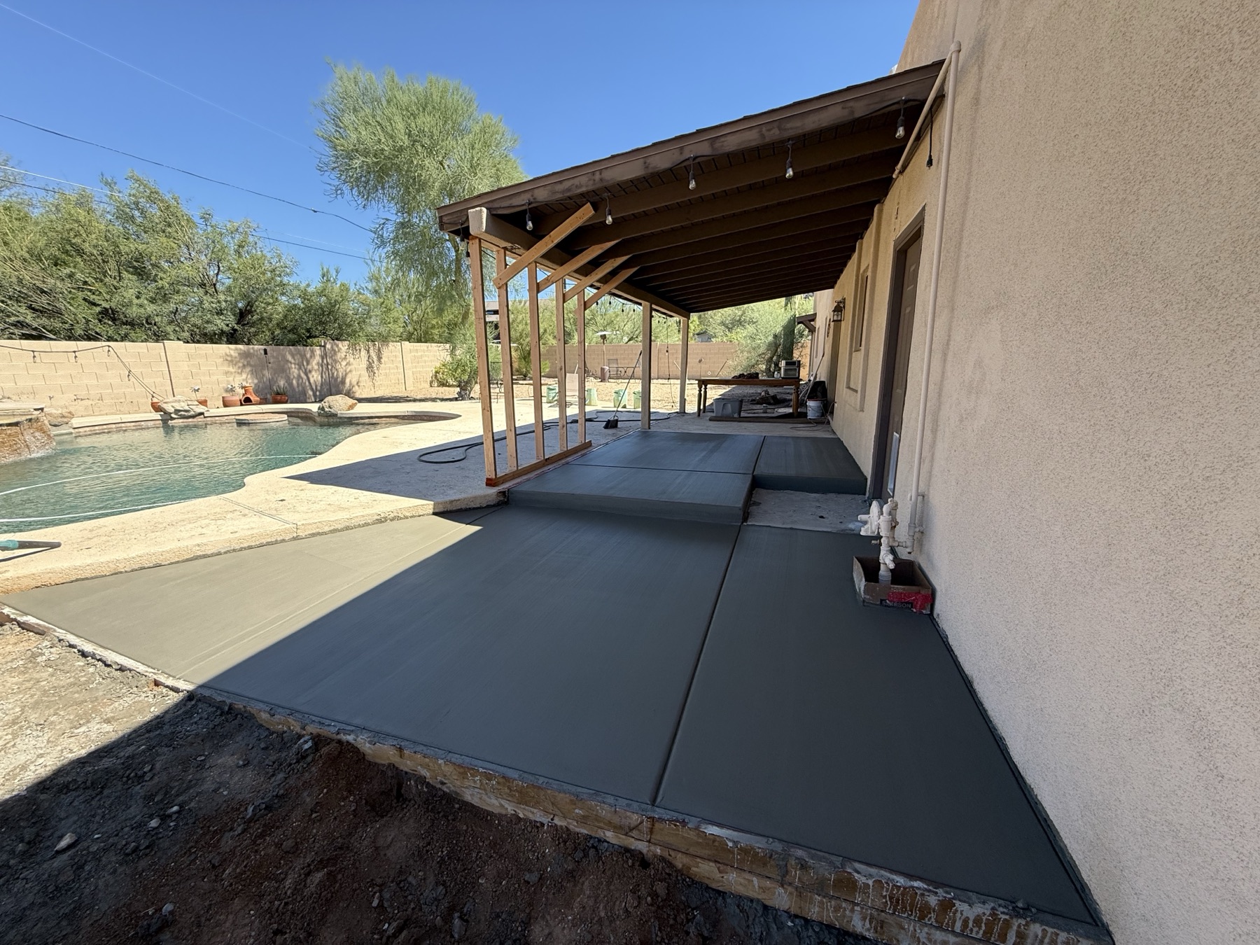 Charcoal stained concrete patio beside pool
